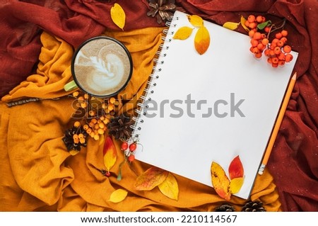 Autumn home cozy composition with yellow and burgundy blankets, cup of coffee, red and yellow leaves and notebook with copy space. Fall season template for feminine blog social media. Royalty-Free Stock Photo #2210114567