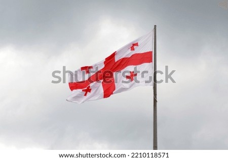 The national flag of Georgia flutters against the backdrop of thunderclouds. Danger and anxiety