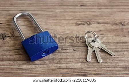 Metal blue padlock and keys on wooden background