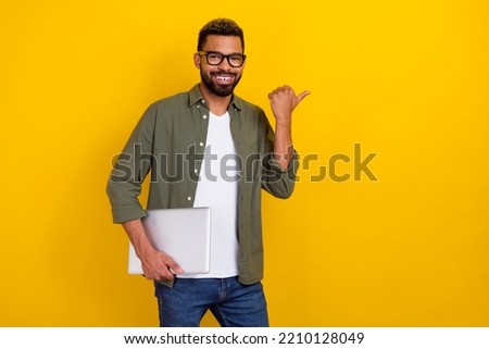 Photo of pretty good mood man wear khaki shirt hand spectacles holding modern device empty space isolated yellow color background