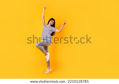 Full length portrait of positive pretty vietnamese girl arms fingers show v-sign empty space isolated on yellow color background