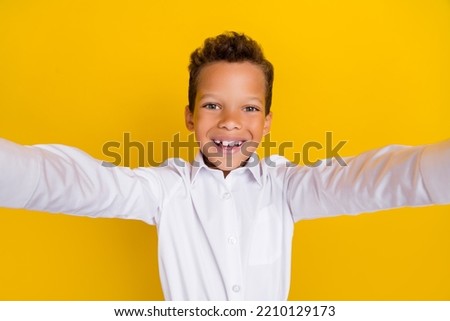 Photo of cheerful attractive boy schoolkid blogger dressed white stylish outfit make photo shooting isolated on yellow color background
