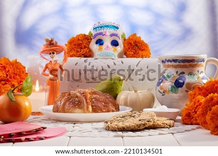 Traditional Mexican offering for the day of the dead with sweets, bread of the dead, aztec marigold flowers, a lit candle and fruit over typical minced paper. Royalty-Free Stock Photo #2210134501