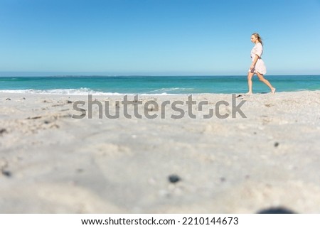 Side view low section of a Caucasian woman on the beach with blue sky and sea in the background, walking on the sand Royalty-Free Stock Photo #2210144673