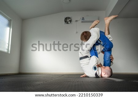 Brazilian jiu jitsu bjj training or sparing two athletes fighters dill martial arts technique at gym on the tatami mats wear kimono gi black belt instructor demonstrate submission armbar juji gatame Royalty-Free Stock Photo #2210150339