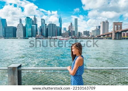 New York city Manhattan skyline seen from Brooklyn waterfront - woman looking at view. American people walking enjoying view of Manhattan over the Hudson river from the Brooklyn side. NYC cityscape