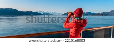 Alaska Glacier Bay cruise ship passenger looking at mountains with binoculars exploring Glacier Bay National Park. Woman on travel Inside Passage enjoying view. Panoramic vacation adventure banner. Royalty-Free Stock Photo #2210168003