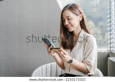Asian woman using laptop and online shopping credit card at a coffee shop