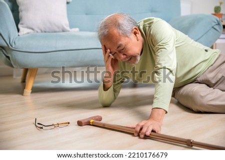 Sick senior old man falling down lying on the ground because stumbled at home alone with wooden walking stick in living room, elderly man grandfather having accident while walk with cane walker