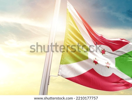 Burundi national flag cloth fabric waving on the sky with beautiful sunlight - Image