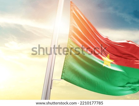 Burkina Faso national flag cloth fabric waving on the sky with beautiful sunlight - Image