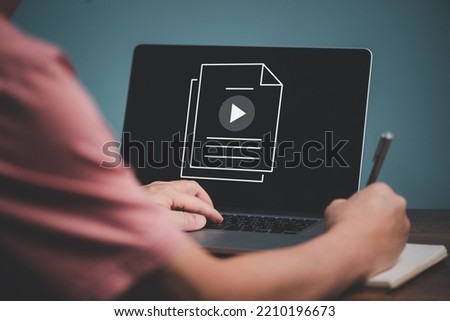 E learning concept. Casual business man studying online course via website or page on computer and writing on notebook.
