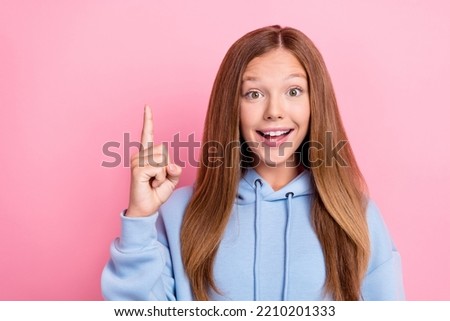 Portrait photo of young pretty nice funny childish lady teen wear blue hoodie excited good mood has genius idea finger point up isolated on pink color background