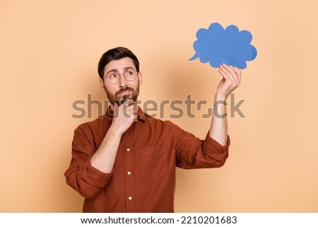 Portrait of minded clever man arm touch chin look empty space hold cloud figure isolated on beige color background