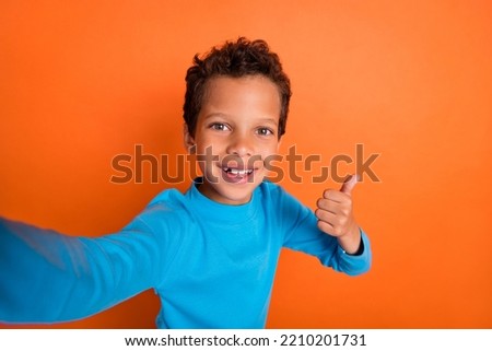 Photo portrait of adorable little boy video call show thumb up good job feedback wear trendy blue look isolated on orange color background