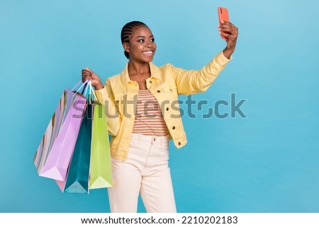 Portrait of attractive trendy cheery girl holding bags using device taking selfie isolated over bright blue color background
