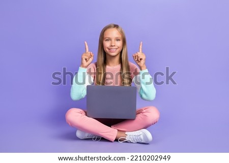Full length photo of cheerful girl sit floor hand show empty space recommend offer device shop sale isolated on purple color background