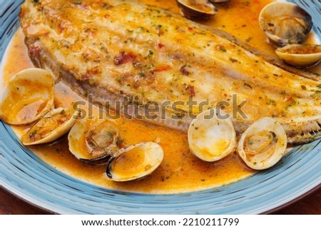 Delicious cooked clams and halibut in a buttery sauce on a plate.