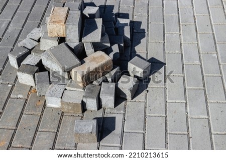 Pavement repairs and paving slabs laying on the prepared surface, with tile cubes in the background. Laying paving slabs in the pedestrian zone of the city. Paving slabs and curbs