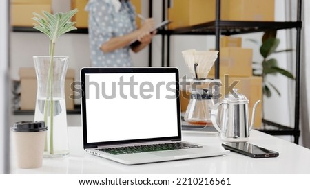 Blank screen mock up laptop computer, Young woman working in the background.