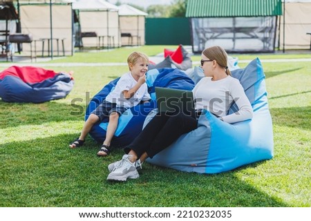 Mother and son on a soft bean bag chair. Mom and son in a bag chair in nature.