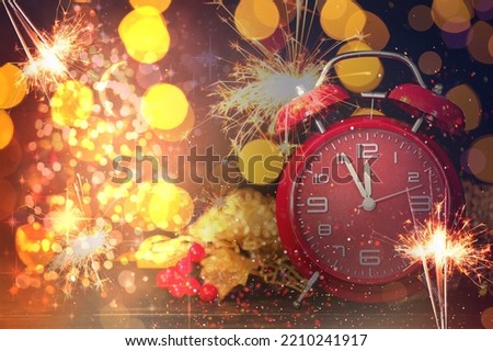 Festive collage of alarm clock, Christmas sparklers and blurred lights on dark background. New Year celebration