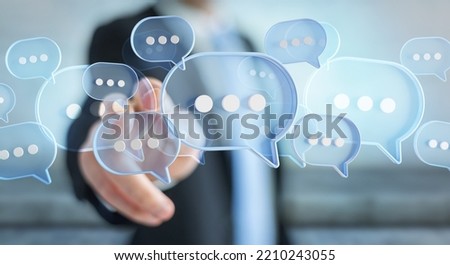 Man touching with his fingers digital blue speech bubbles talk icons. Minimal conversation or social media messages floating in front of businessman hand. 3D rendering Royalty-Free Stock Photo #2210243055