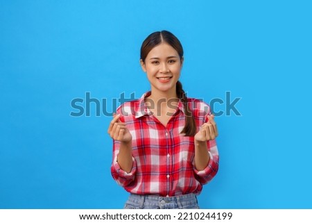 Women are smiling and doing gesture of mini heart isolated on light blue background.