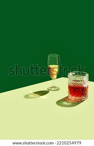Glass of Champagne and a Glass of Whiskey on a Green Background