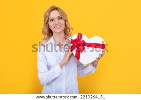 positive woman with present heart box on yellow background