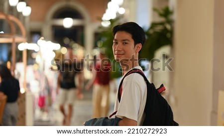 Portrait of hipster man standing in city avenue with blurred night street lights background