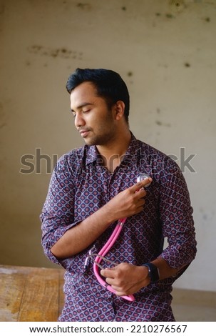 South asian young male doctor holding a stethoscope wearing shirt 