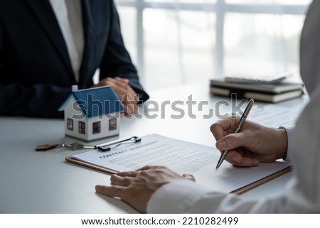 Real estate brokers point to a contract paper with her pen and advise customers to sign their names. Real estate agent, property broker, real estate investment buy and sell concept.