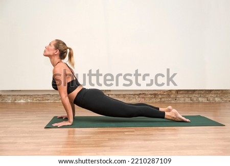 a young woman stretching in Cobra pose, doing Bhujangasana exercise, practicing yoga