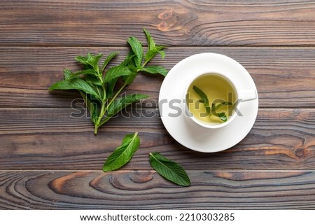 Cup of mint tea on table background. Green tea with fresh mint top view with copy space.