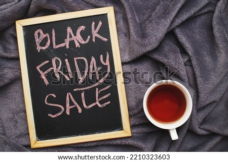 friday sale announcement on a blackboard on grey textile plush fabric wrinkled background with cup of tea.