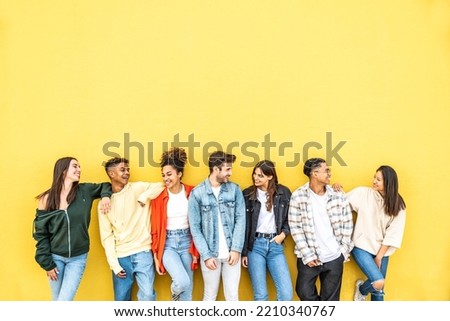 Diverse community of young people smiling together on a yellow wall background - Multiracial college students having fun laughing outside - Youth culture concept Royalty-Free Stock Photo #2210340767