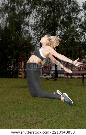 Full length of a healthy beautiful young woman in sportswear jumping in the park