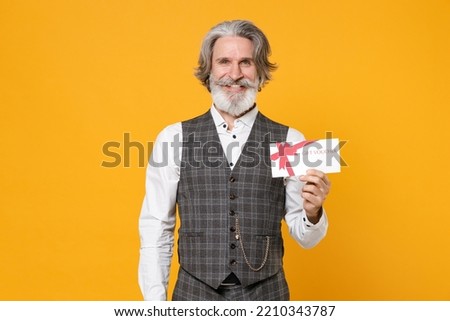 Smiling elderly gray-haired mustache bearded business man in checkered waistcoat white shirt hold gift certificate isolated on yellow background studio portrait. Achievement career wealth concept