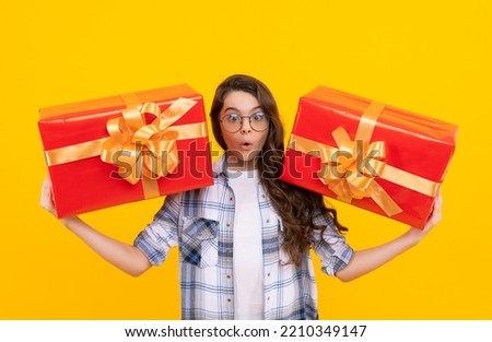 shocked teen kid with present isolated on yellow background. teen kid in glasses with present.