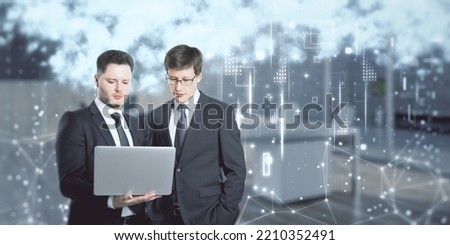 Young european businessmen with laptop and creative cloud data icons on blurry background. Cloud computing, teamwork, big data, technology and database concept. Double exposure