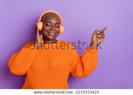 Photo of lovely young woman enjoy melody headphones promo wear stylish fall orange knitted sweater isolated on purple color background