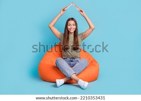 Full length photo of adorable cute lady sit comfort chair dressed stylish clothes enjoy holiday weekend home isolated on blue background