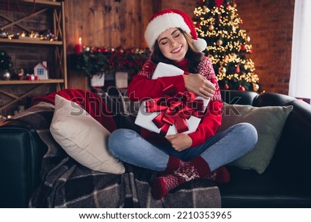 Full size portrait of cheerful lovely girl arms hold hug giftbox closed eyes enjoy newyear house indoors