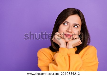 Closeup photo of young adorable girlish pretty woman wear orange sweater touch cheeks dreamy interested look empty space isolated on violet color background