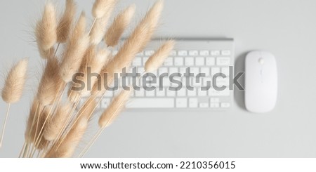 Dry fluffy rabbit tail flower and keyboard on background of gray office table. Autumn, fall business concept. Flat lay, mockup