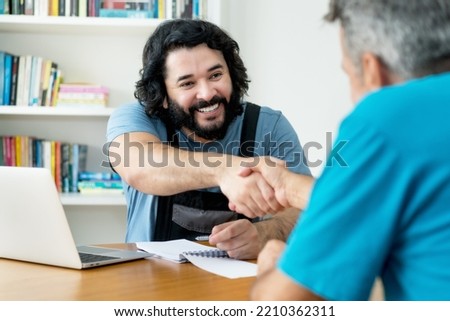 Handshake of handyman and customer after signing a conract at workplace Royalty-Free Stock Photo #2210362311