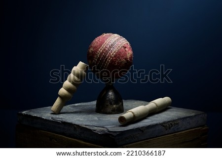 Cricket ball and bails still life in moody light with a blue background
