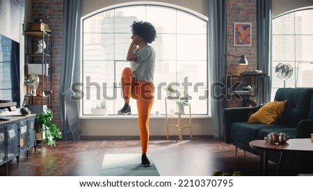 Concentrated Positive Black Woman Doing Cardio, High Knees and Squat Exercises During Daily Workout at Cozy Home. Strong and Fit Girl Committing to Healthy Lifestyle. Fitness and Recreation Concept.
