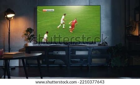 Shot of a TV with Soccer Match on Big Flat Screen Televison Set. Live Broadcast of Football World Championship Finals on Sports Channel. Cozy Game Night in Strylish Loft Apartment Living Room. Royalty-Free Stock Photo #2210377643